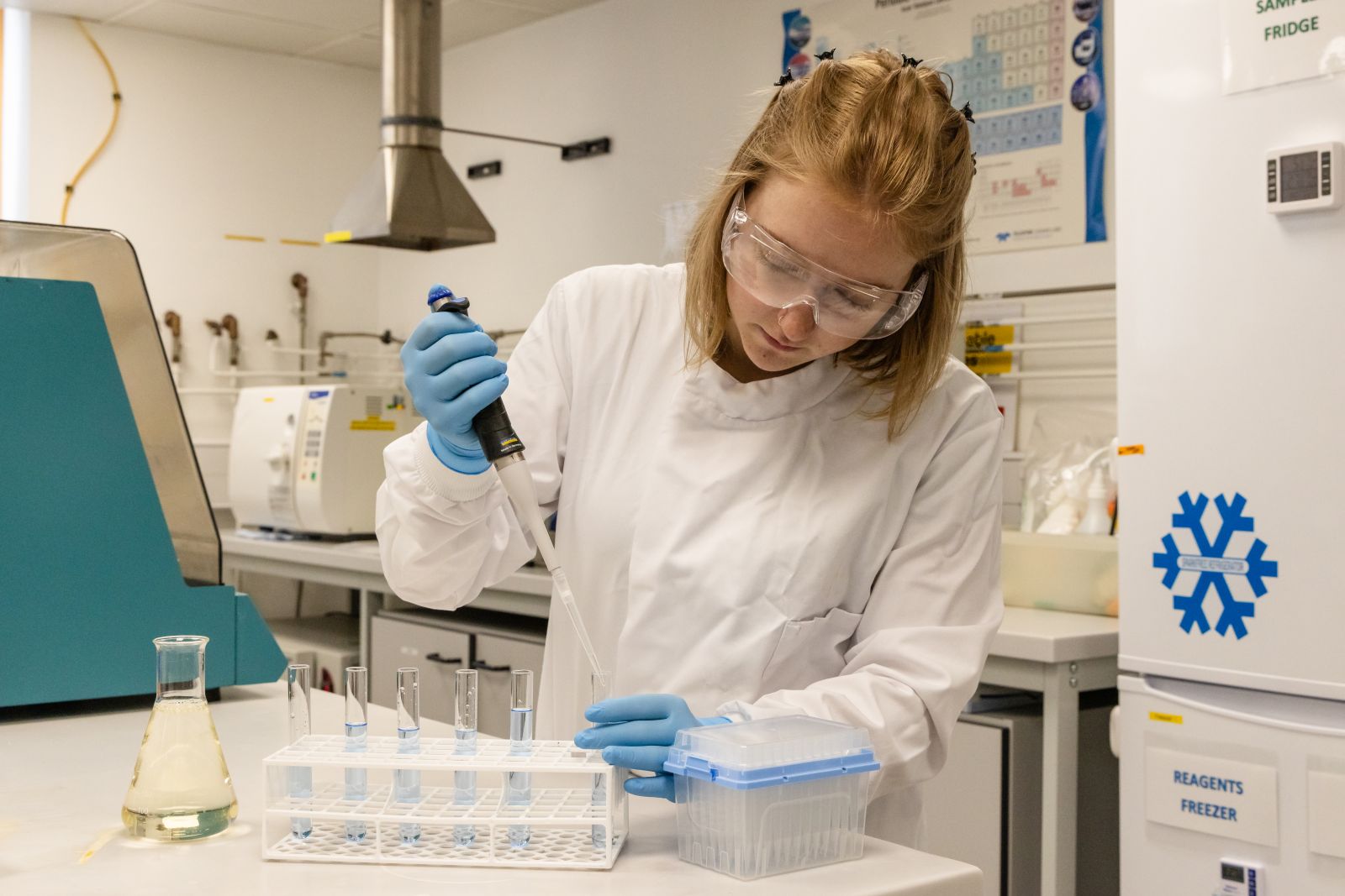 Person in lab conducting an experiment using test tubes